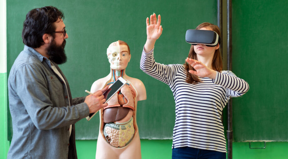 Professeur utilisant une tablette et un masque de realite virtuelle pour enseigner la biologie a une eleve lyceenne